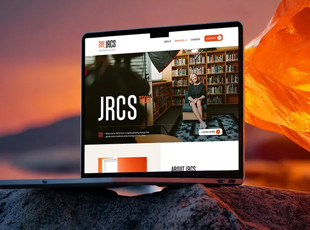 A smiling woman in a business suit holding a tablet in front of a wooden wall.